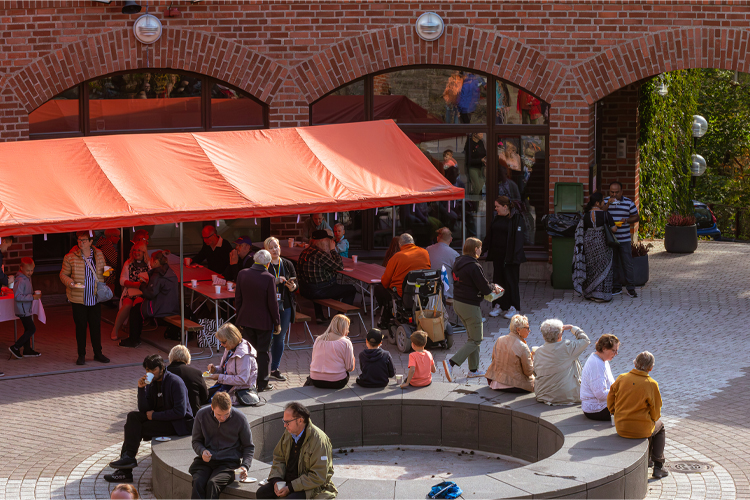 Människor sitter utomhus en solig sommardag och umgås.