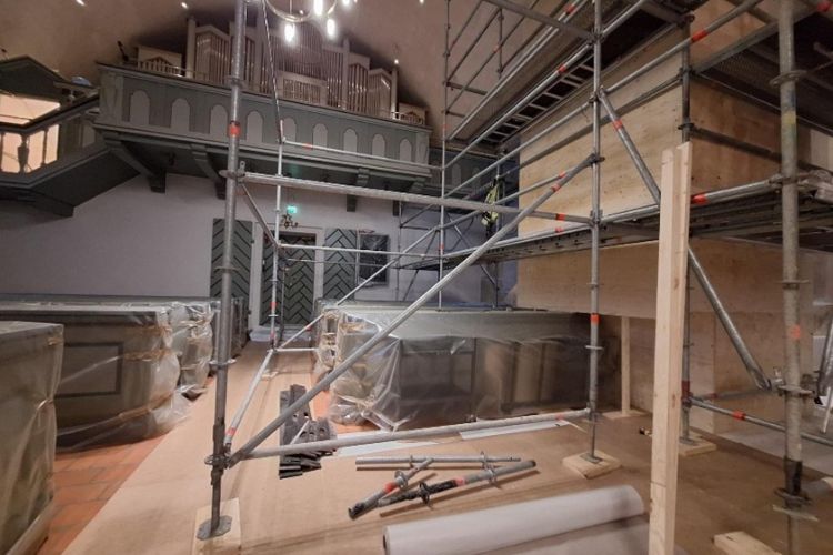 Orgelläktaren syns och plastövertäckt interiör i kyrkorummet.