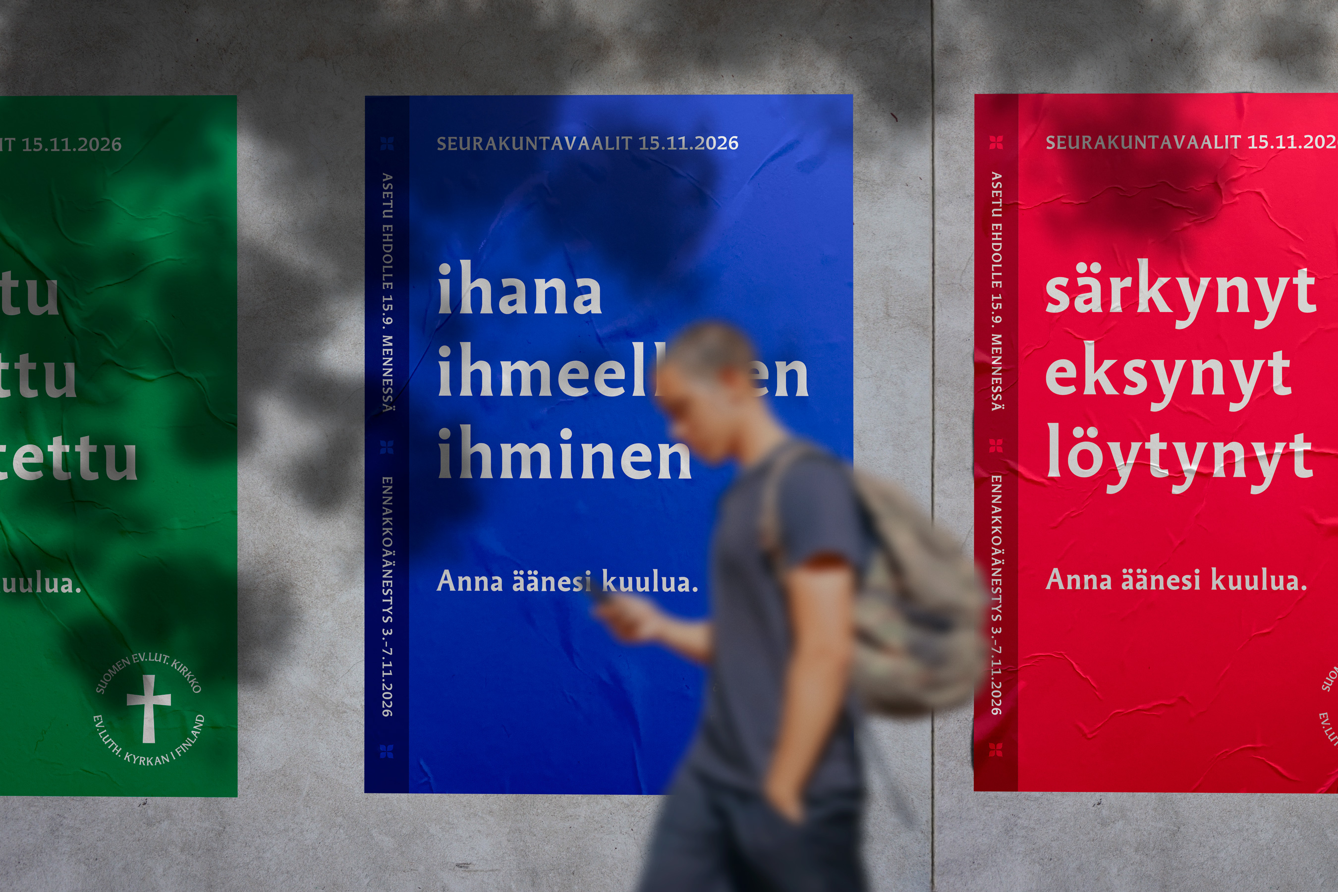 Tre affischer i olika färger med texter. I bakgrunden går en person som är suddig.