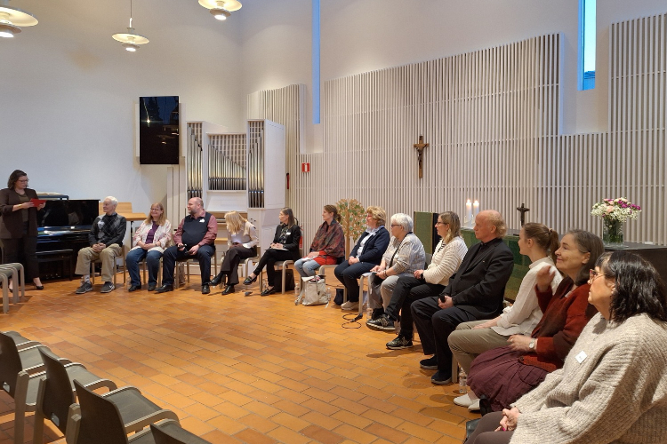 Kandidater sitter i en halvcirkel framför altaret i Olars kyrka.