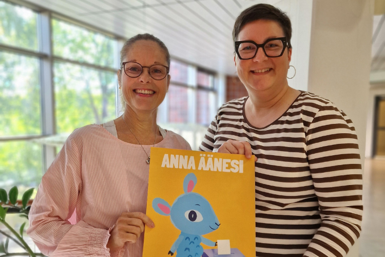 Två kvinnor håller en affisch med texten: Anna äänesi (ge din röst) och illustration med ett ljusblått lamm.