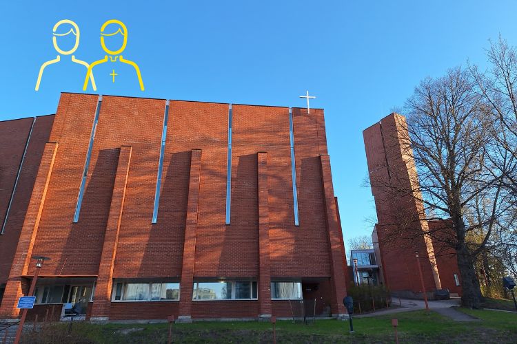 En stor rödtegelbyggnad med ett vitt kors på taket fotograferad i morgonsol och klarblå himmel.