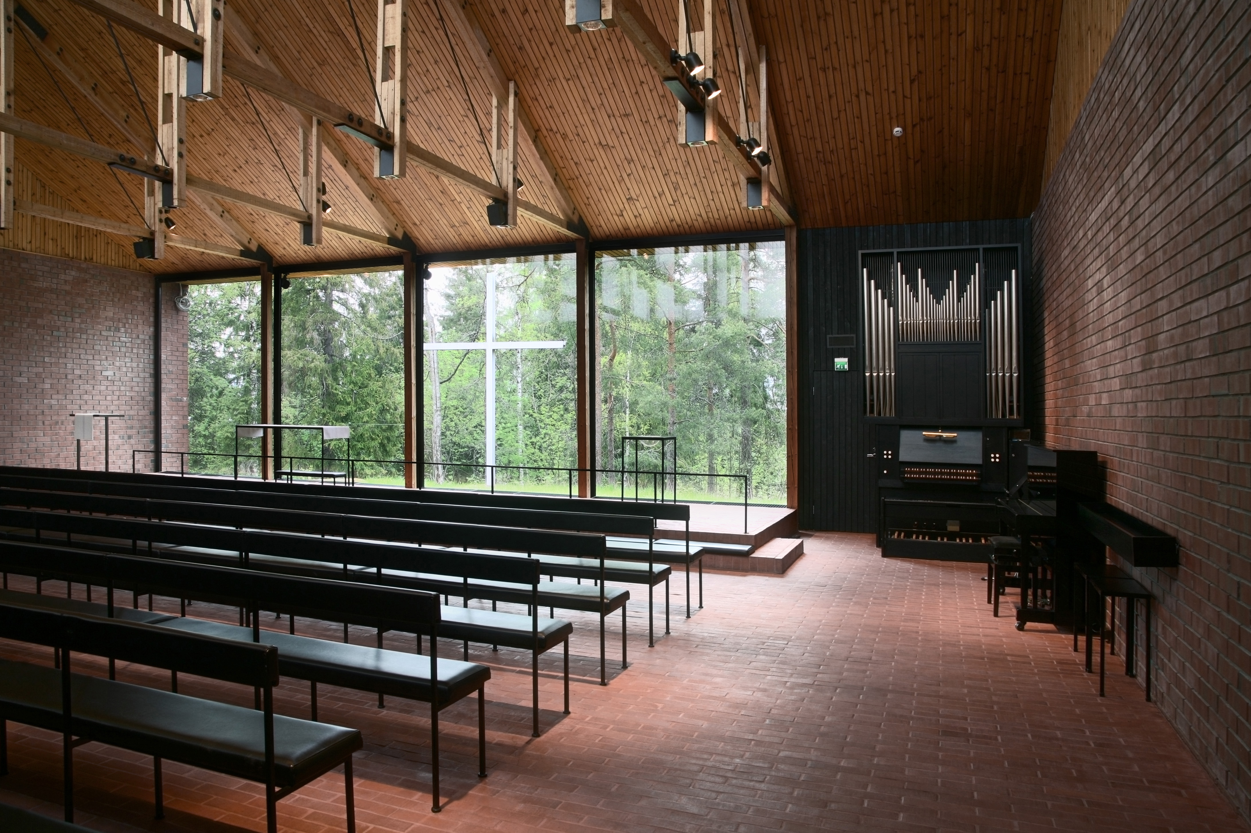 En kyrksal i avskalad modern arkitektur med en glasvägg ut mot naturen.