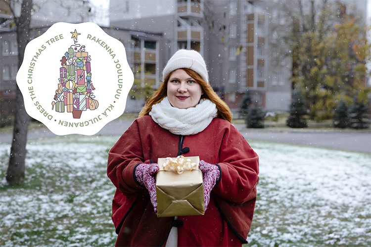 En kvinna i vit yllemössa och röd cape håller ett paket i sina händer och i bakgrunden höghus med en snöig ...
