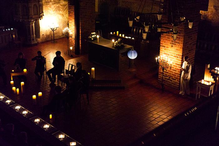 Musiker sitter som mörka figurer i ett svagt upplyst kyrkorum.