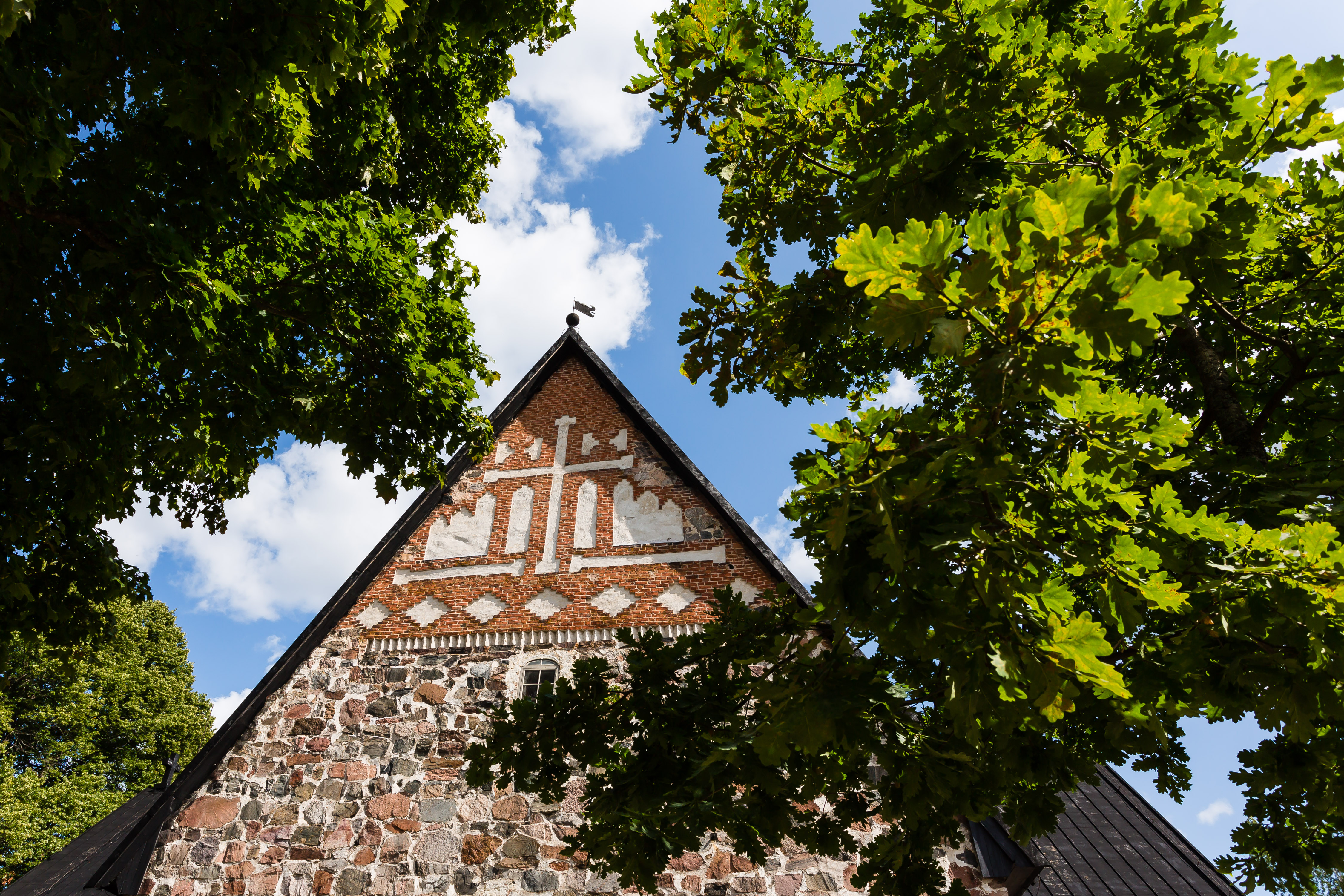 Högmässa Esbo domkyrkas gavel omgiven av gröna träd.