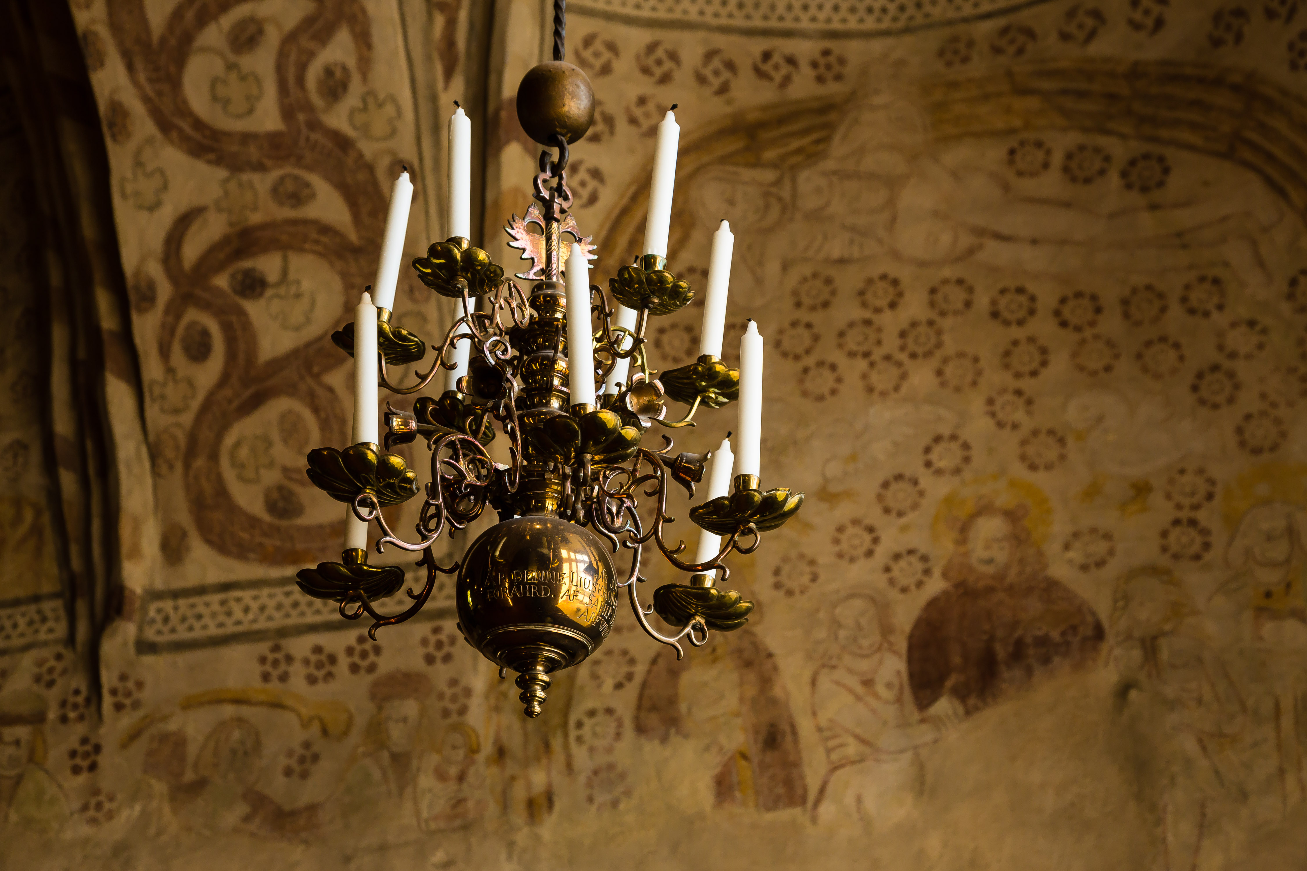 Mässa med medeltida inslag Takkrona av mässing i Esbo domkyrka mot bakgrunden av de medeltida valvmålningarna.