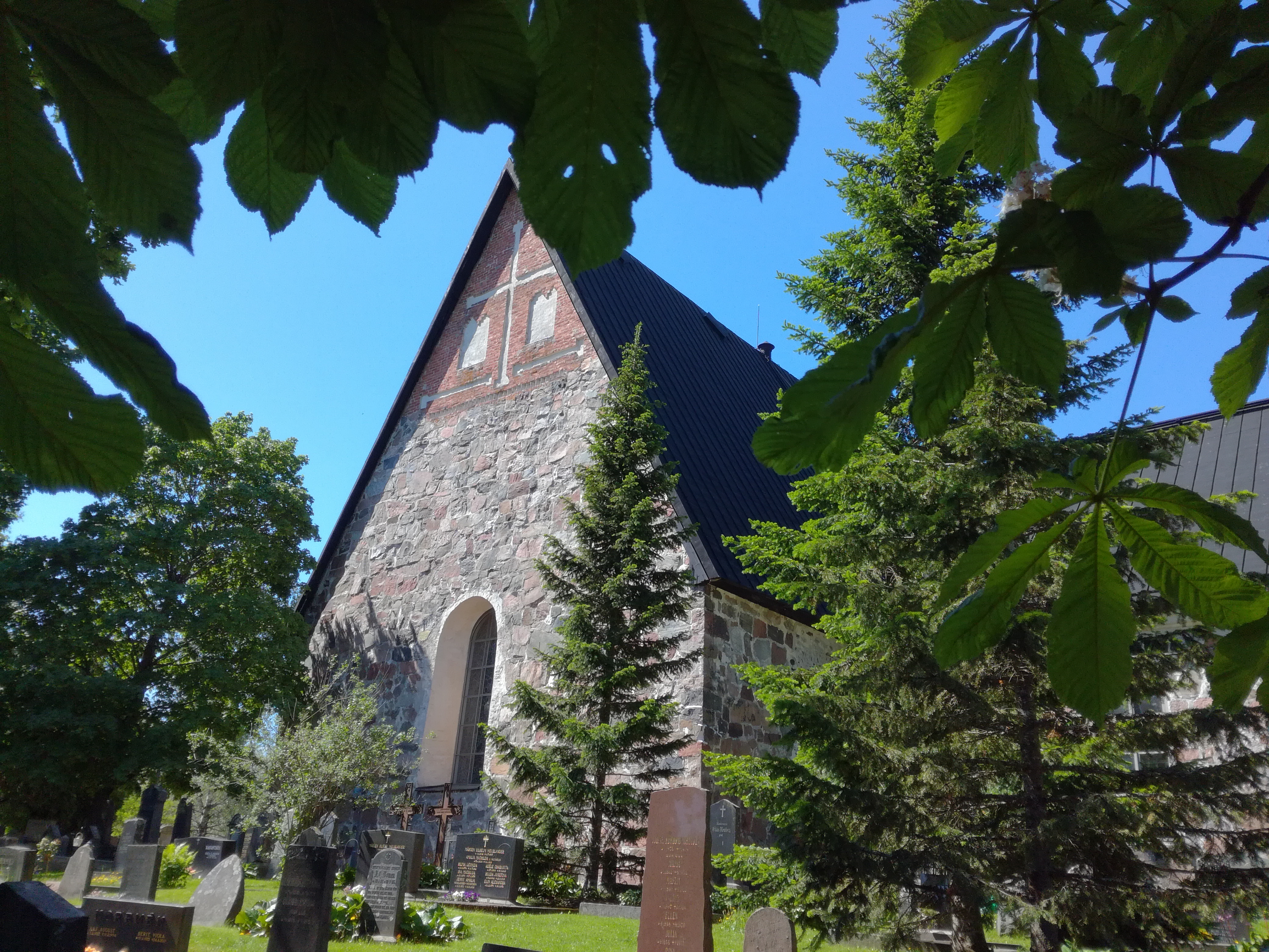 Högmässa Esbo domkyrka sommartid, omgiven av träd.