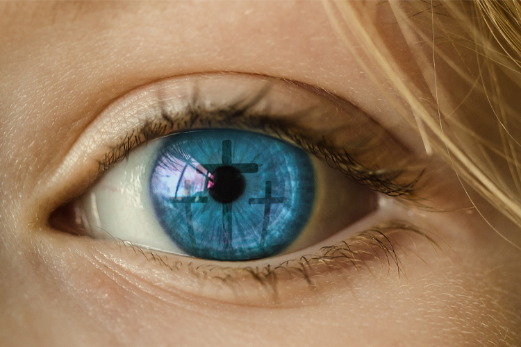 Ett öga i närbild och i den blå pupillen speglas tre kors.