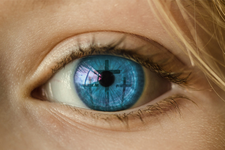 Ett öga i närbild där tre kors syns eller speglas i pupillen.