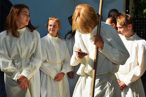 Konfirmander klädda i albor utanför en kyrka.