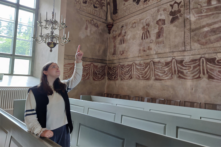 Kyrkguide Olivia Lerche pekar upp i valvet där de medeltida målningarna syns.