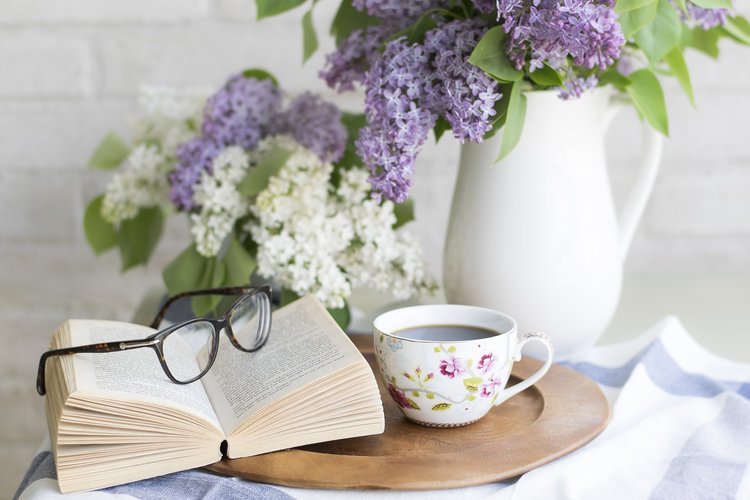 Syrenkvist, kaffekopp, bok och glasögon.