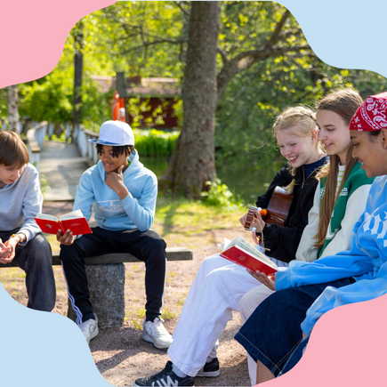 Flickor och pojkar sitter utomhus i grönska med Biblar i händerna.